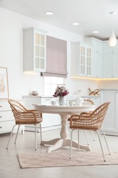 Dining room interior with tea set on round table and wicker chairs