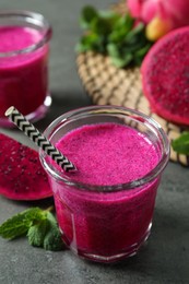 Photo of Delicious pitahaya smoothie, fruits and fresh mint on grey table