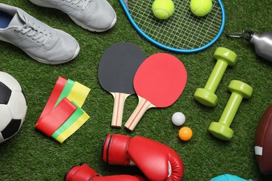 Flat lay composition with sports equipment on green grass