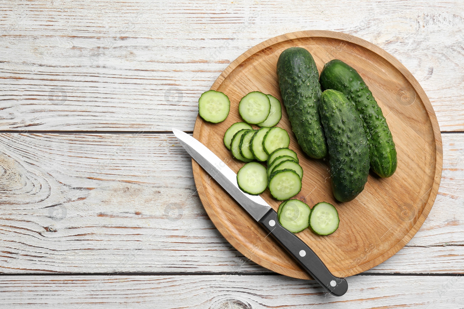 Photo of Whole and cut fresh ripe cucumbers on white wooden table, flat lay. Space for text