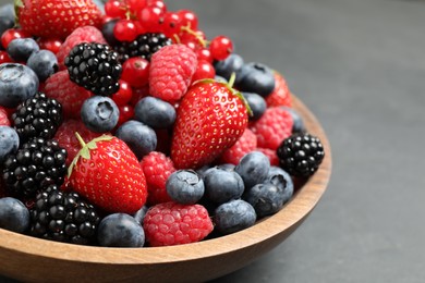 Photo of Mix of different fresh berries in bowl on grey table, closeup