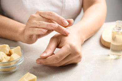 Photo of Woman applying organic cocoa butter at table, closeup