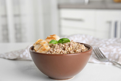 Photo of Tasty buckwheat porridge with meat on white table indoors