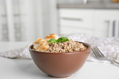 Tasty buckwheat porridge with meat on white table indoors