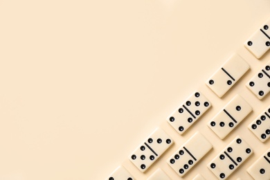 Photo of Classic domino tiles on beige background, flat lay. Space for text