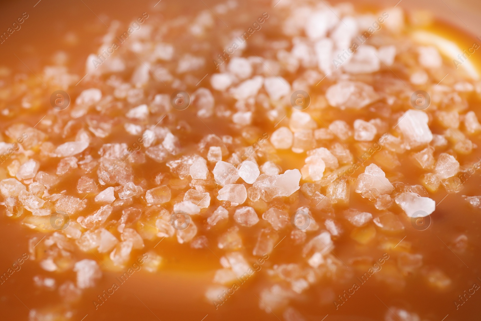 Photo of Delicious caramel sauce with sea salt as background, closeup