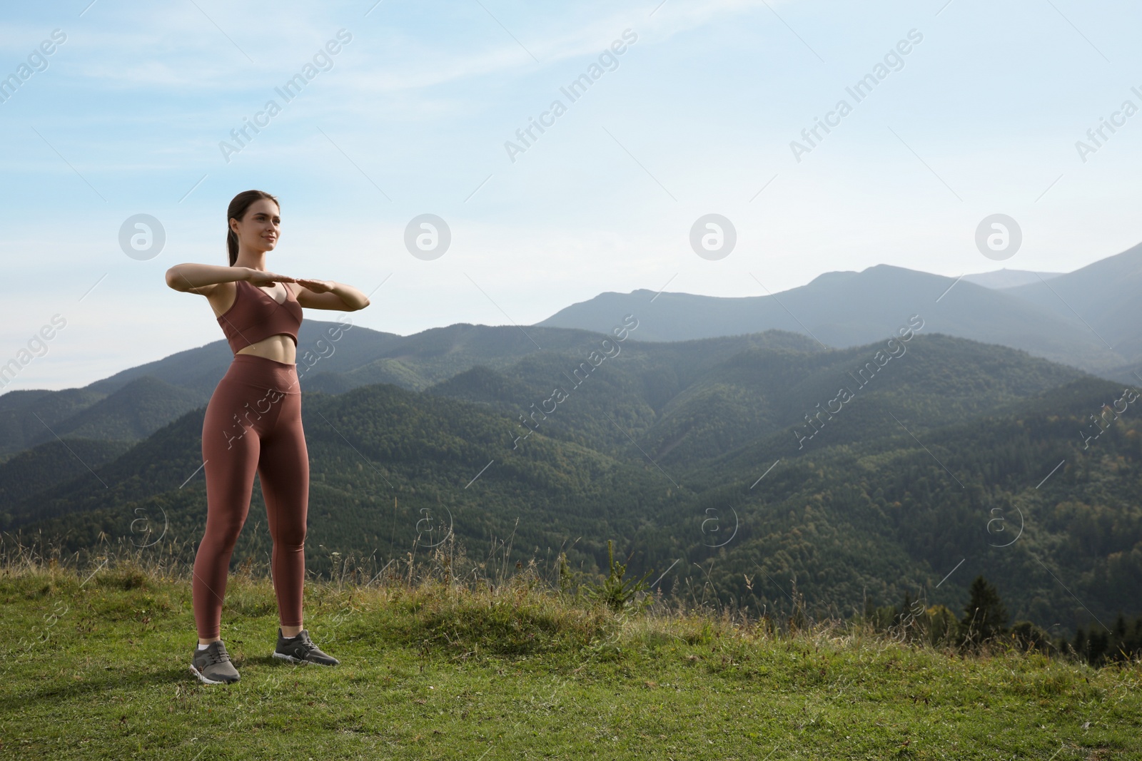 Photo of Young woman doing morning exercise in mountains, space for text