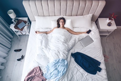 Photo of Tired woman sleeping in bed at home after work, above view