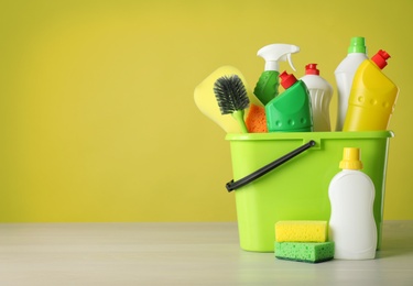 Photo of Bucket with cleaning products and tools on grey table. Space for text