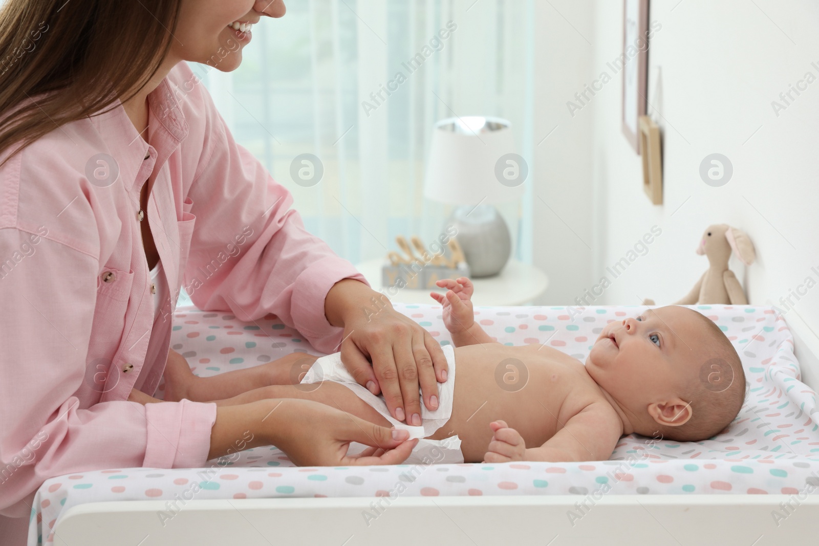 Photo of Mother changing her baby's diaper on table at home