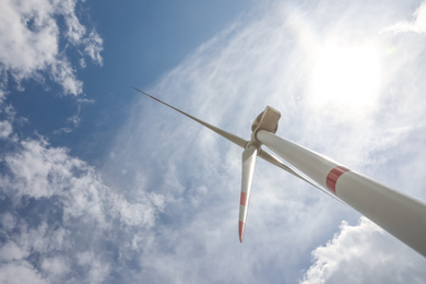 Photo of Modern wind turbine against cloudy sky, low angle view. Alternative energy source