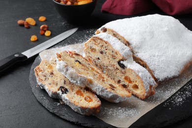 Traditional Christmas Stollen with icing sugar on black table