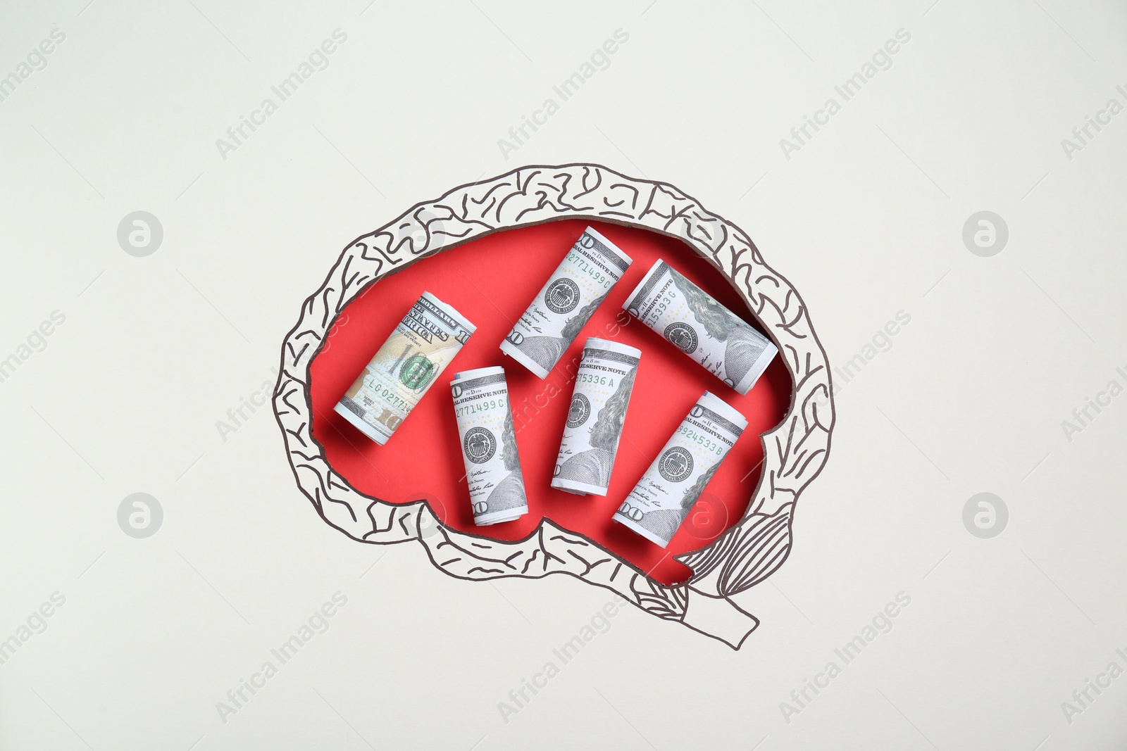 Photo of Rolled dollar banknotes on red background, top view through paper with brain shaped hole and drawing