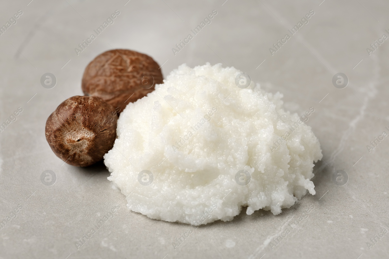 Photo of Shea butter and nuts on grey background, closeup