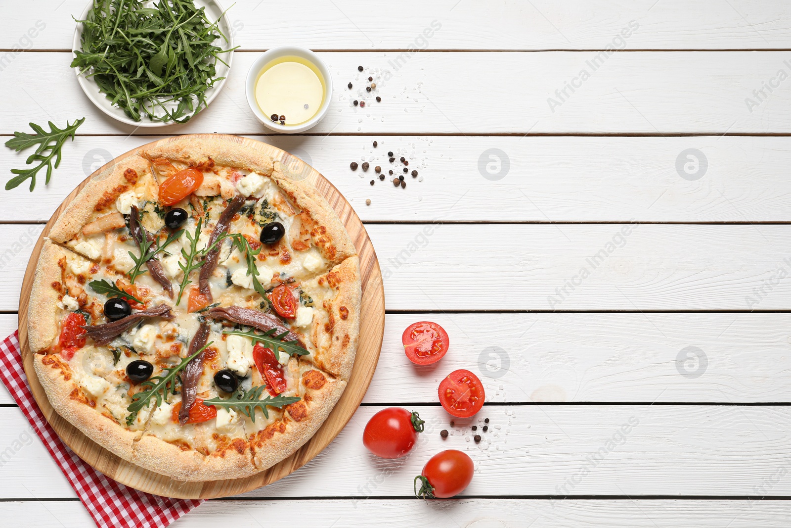 Photo of Tasty pizza with anchovies and ingredients on white wooden table, flat lay. Space for text