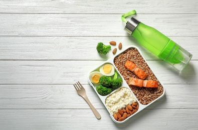 Photo of Container with natural healthy lunch, bottle of water and space for text on table, top view. High protein food