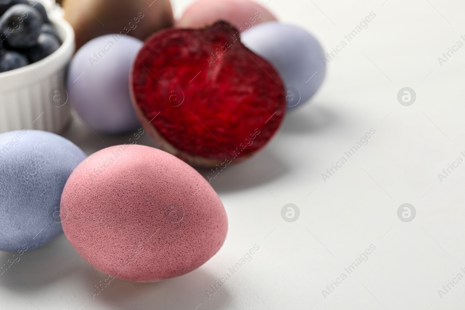Photo of Colorful Easter eggs painted with natural dyes on white table, closeup. Space for text