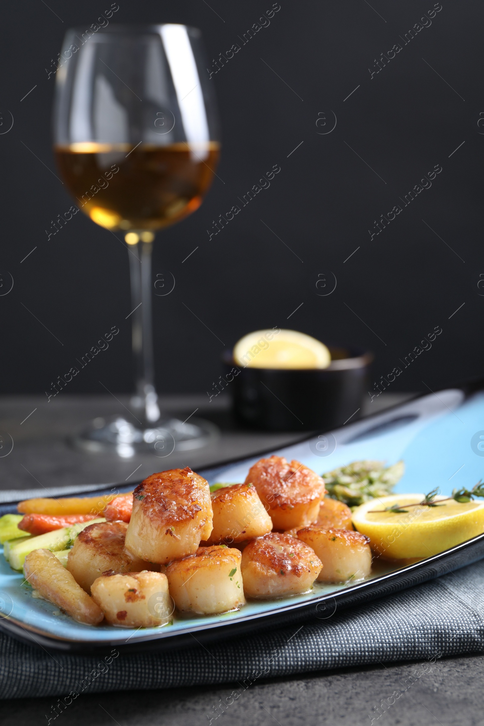 Photo of Delicious fried scallops with asparagus served on grey table