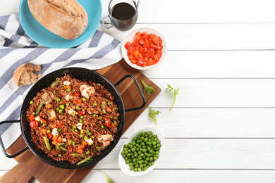 Photo of Tasty brown rice with vegetables served on white wooden table, flat lay. Space for text