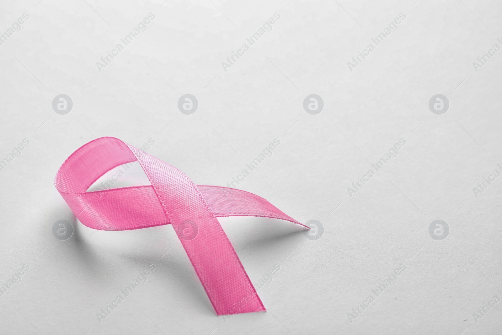 Photo of Pink ribbon on white background, space for text. Breast cancer awareness concept