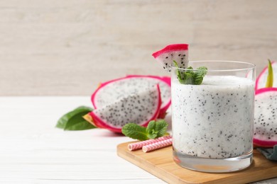 Photo of Glass of tasty pitahaya smoothie with fresh mint on white wooden table, space for text
