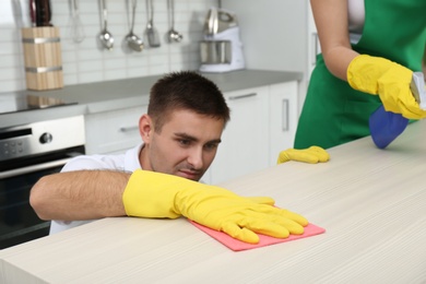 Photo of Team of janitors cleaning table in kitchen