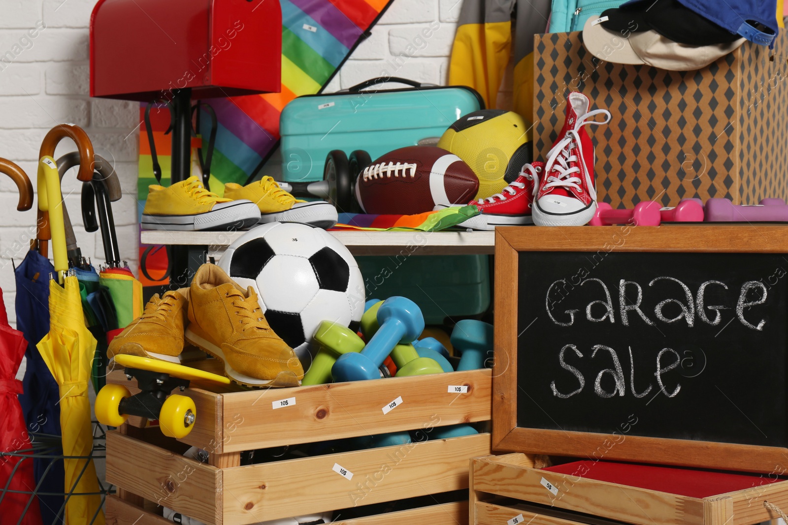 Photo of Sign Garage Sale written on blackboard near many different stuff indoors