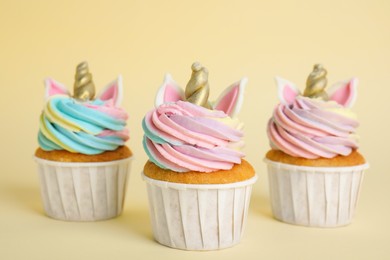 Photo of Cute sweet unicorn cupcakes on beige background