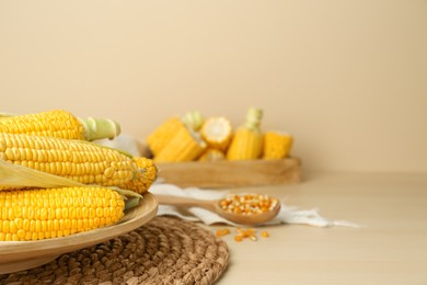 Tasty fresh corn cobs on wooden table, space for text