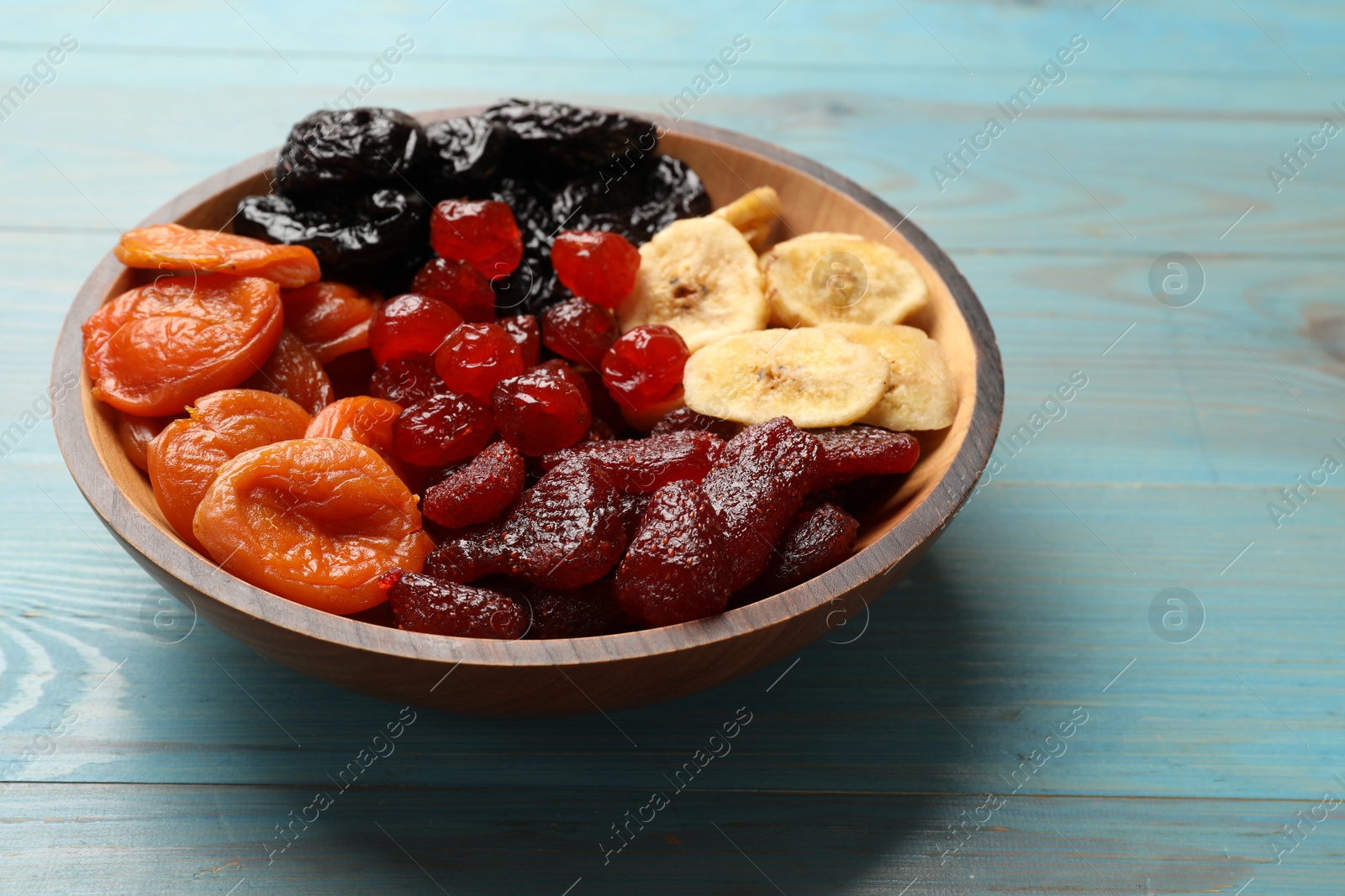 Photo of Mix of delicious dried fruits on light blue wooden table