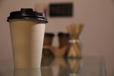 Photo of Takeaway coffee cup with plastic lid on glass table in cafe, closeup. Space for text