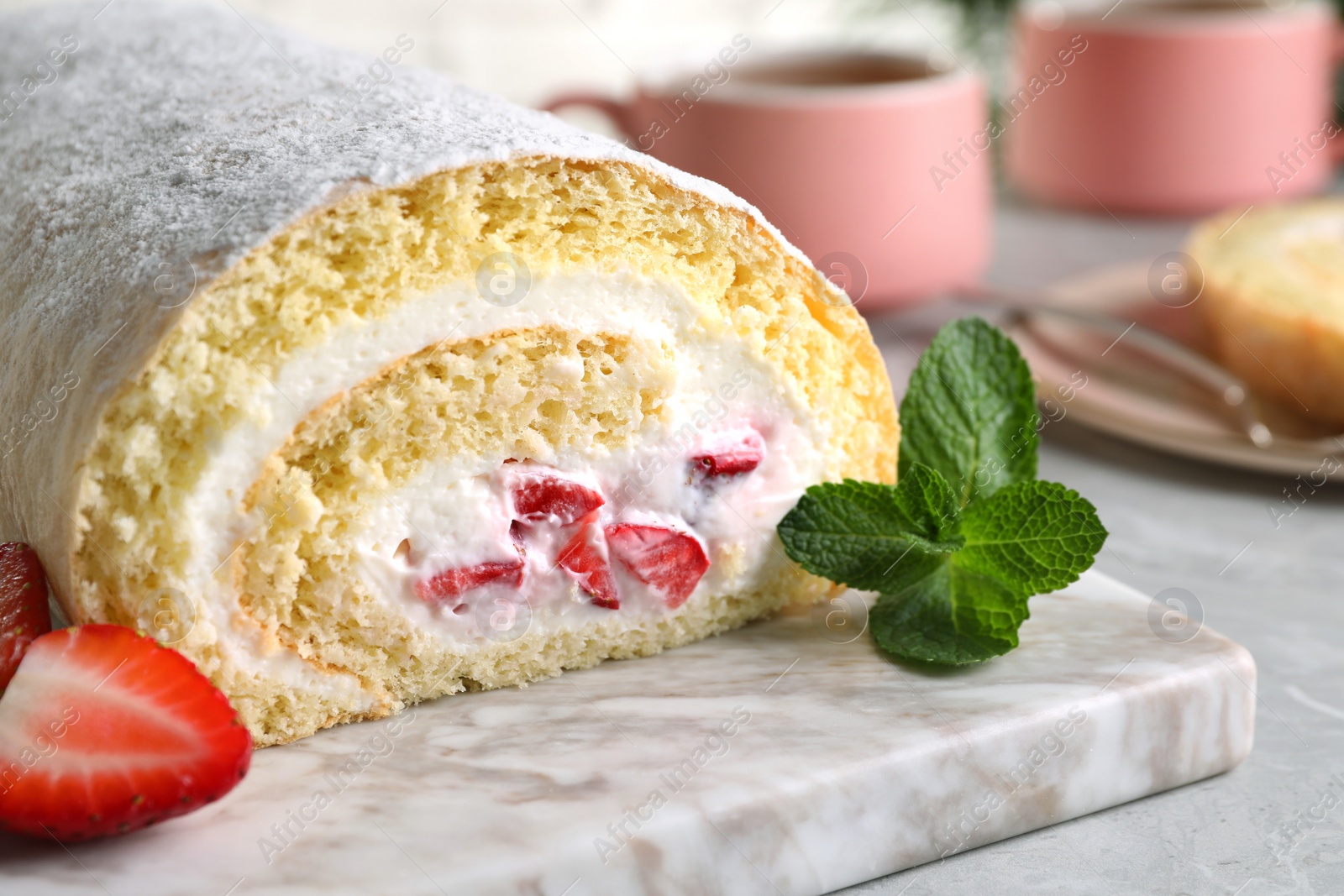 Photo of Delicious sponge cake roll with strawberries and cream on white marble board, closeup