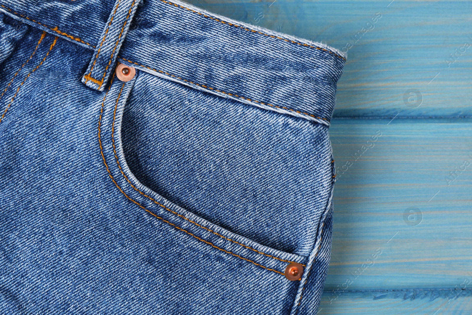 Photo of Stylish blue jeans on wooden background, closeup of inset pocket