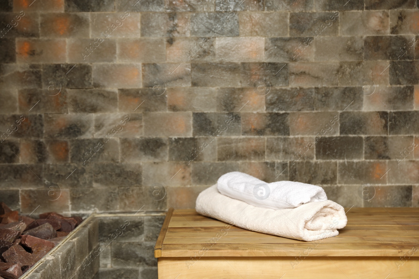 Photo of White towels on wooden bench in salt sauna. Space for text