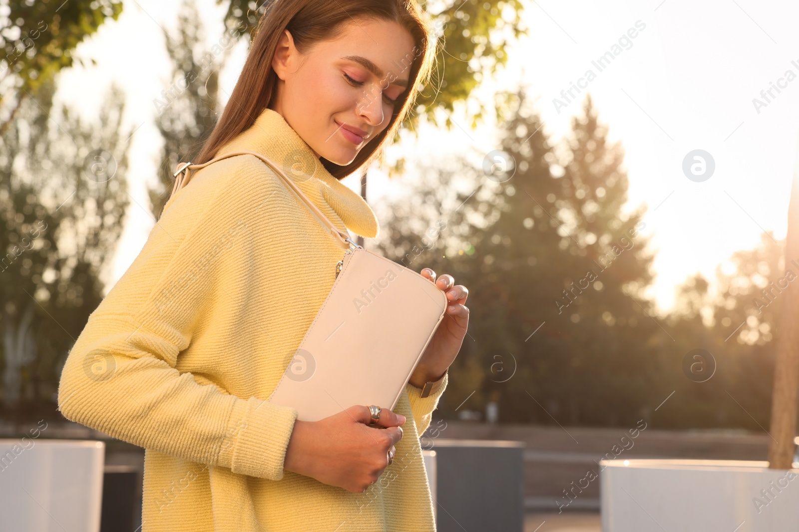 Photo of Fashionable young woman with stylish bag on city street. Space for text