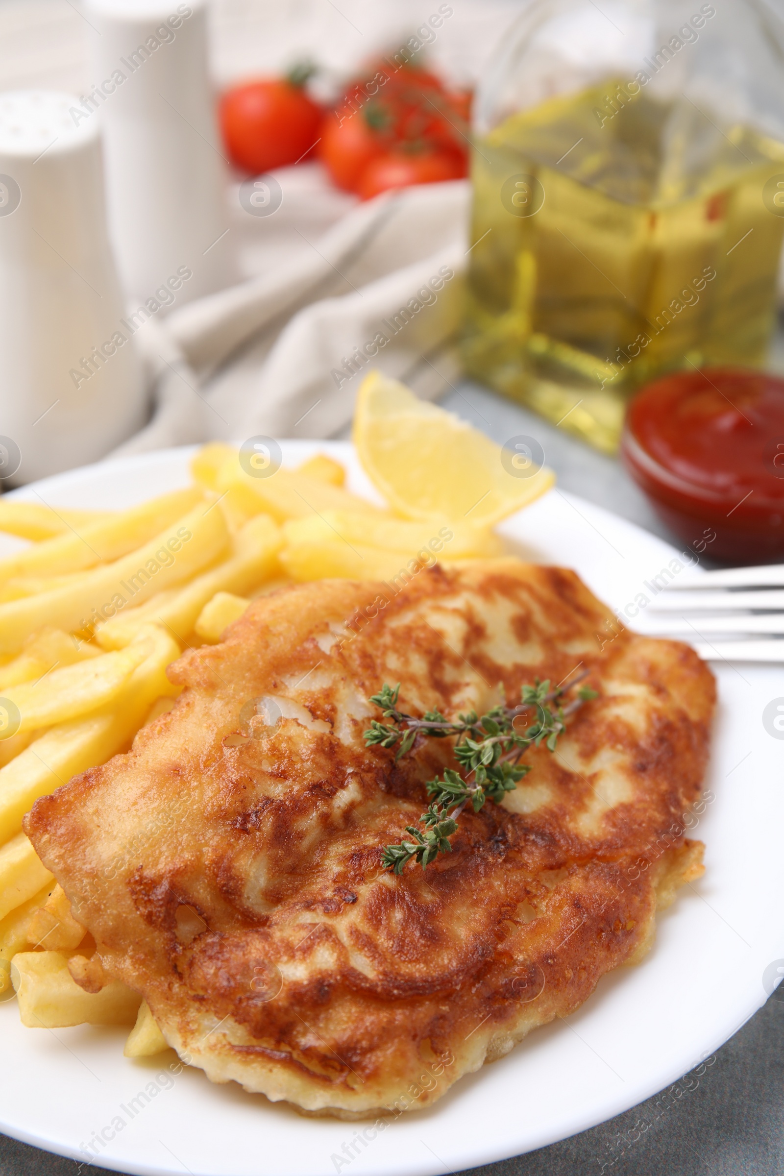 Photo of Tasty soda water battered fish, potato chips and lemon slice on light grey table