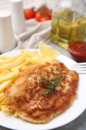 Tasty soda water battered fish, potato chips and lemon slice on light grey table