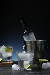 Bottle of vodka, glasses, lime, mint and ice on black marble table