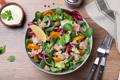 Photo of Bowl of delicious salad with canned tuna and vegetables served on wooden table, flat lay