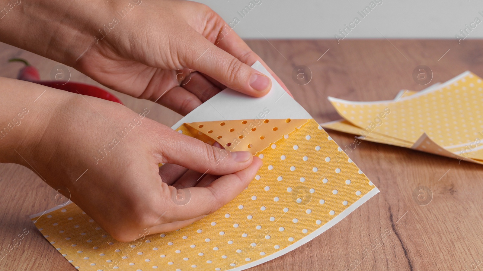 Photo of Woman opening pepper plaster at wooden table, closeup