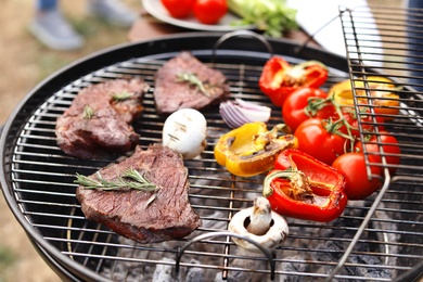 Photo of Modern grill with meat and vegetables outdoors, closeup