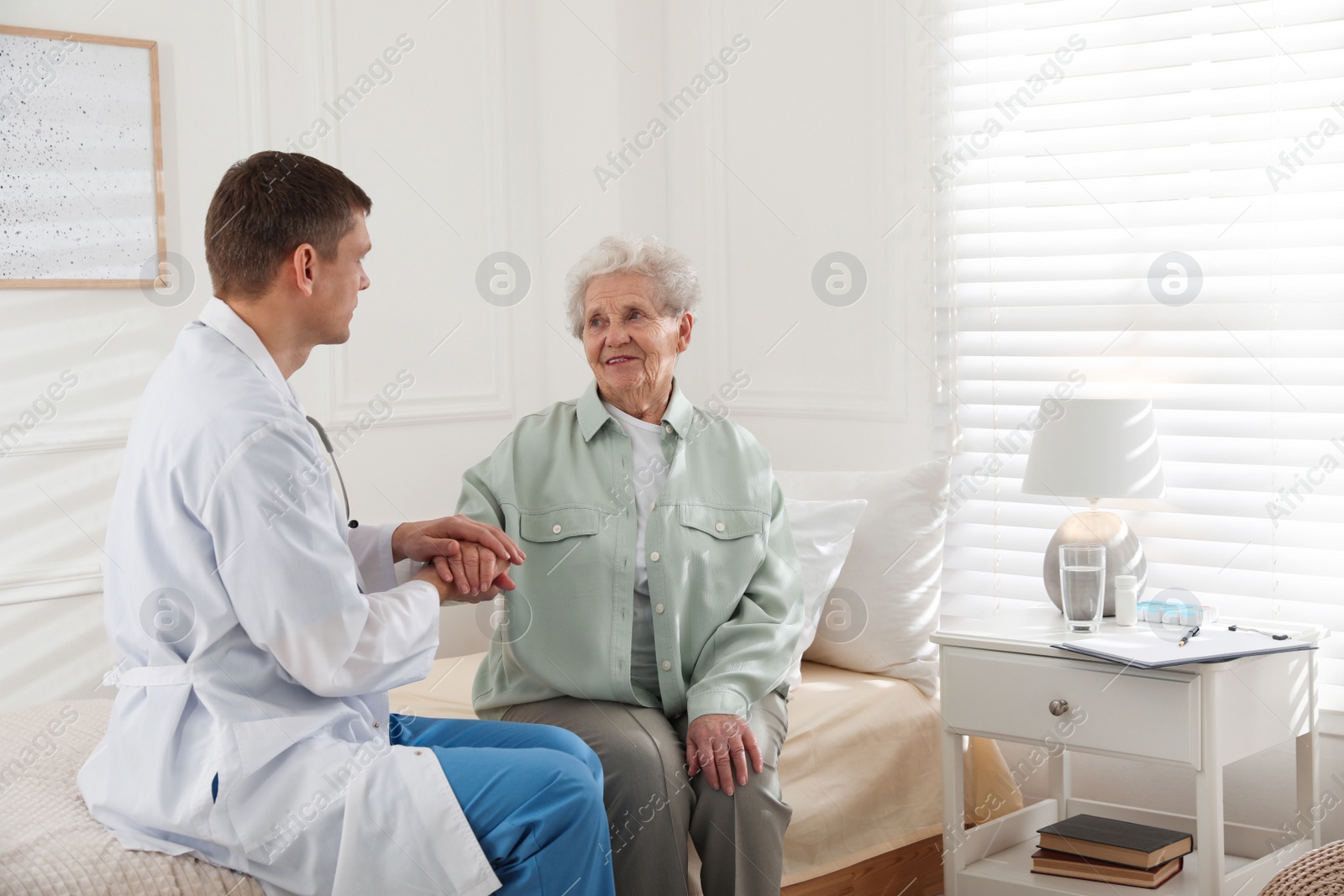 Photo of Caregiver talking to senior woman in living room. Home health care service