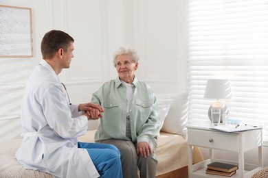 Caregiver talking to senior woman in living room. Home health care service