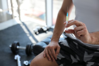 Photo of Sportsman with syringe in gym, closeup. Doping concept