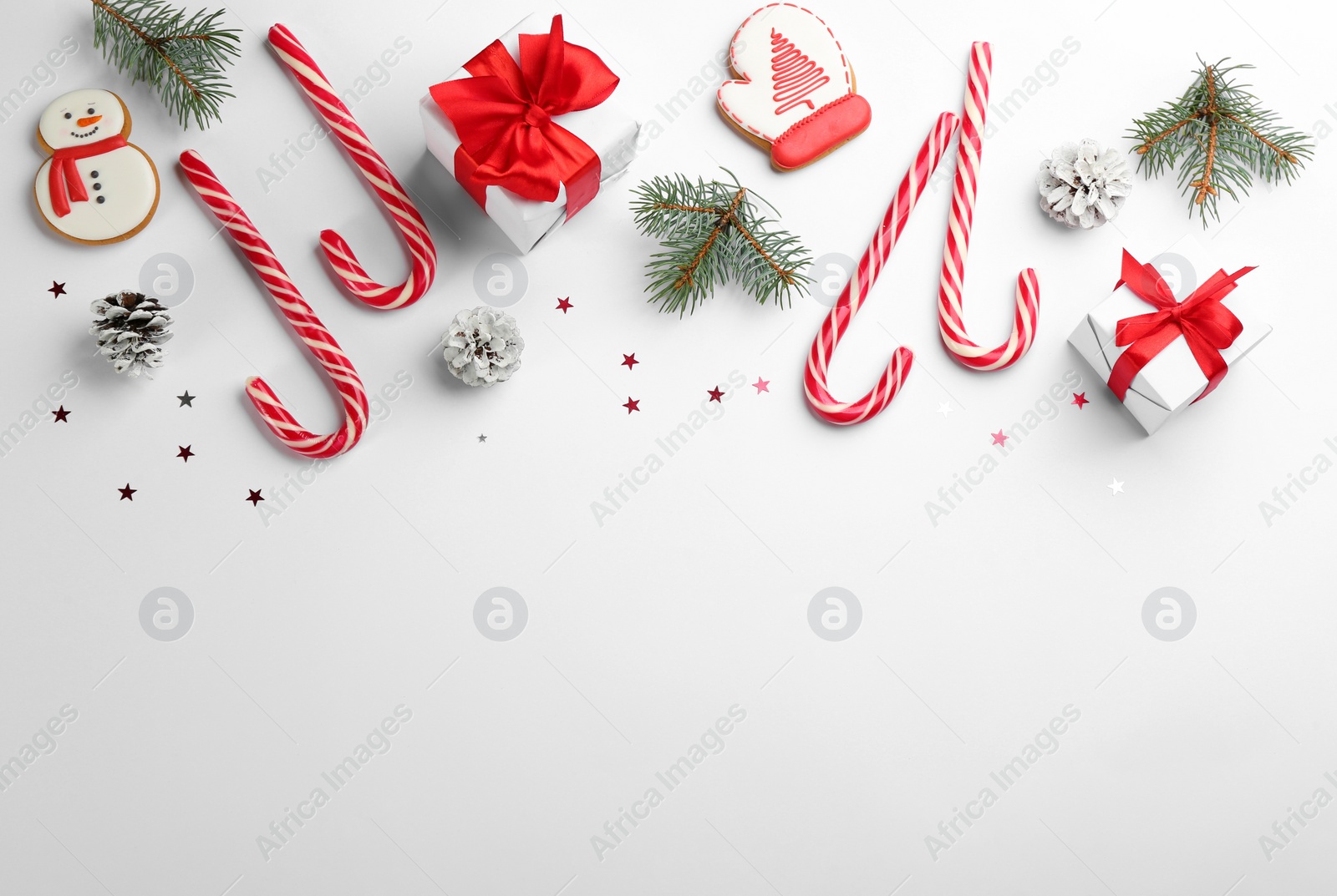Photo of Flat lay composition with candy canes and Christmas decor on white background. Space for text