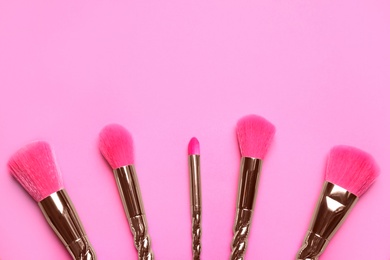 Photo of Set of makeup brushes on pink background, flat lay. Space for text