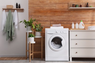 Photo of Laundry room interior with washing machine and stylish furniture