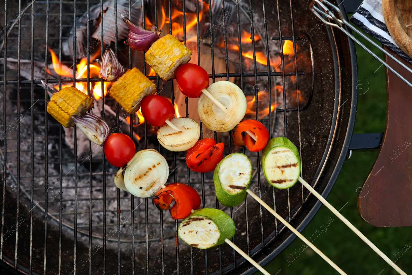 Photo of Skewers with delicious grilled vegetables on barbecue grill outdoors, top view