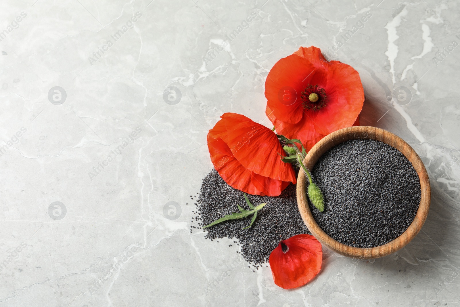 Photo of Wooden bowl of poppy seeds and flower on grey table, flat lay with space for text