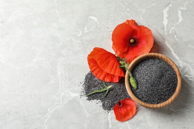 Wooden bowl of poppy seeds and flower on grey table, flat lay with space for text